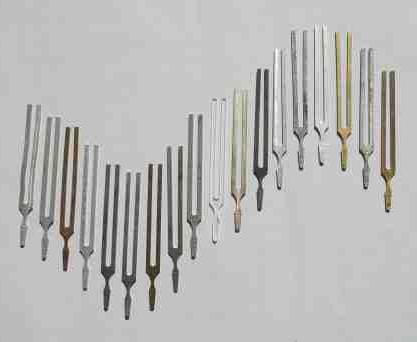 18 tuning forks lying on a table in a sine wave pattern